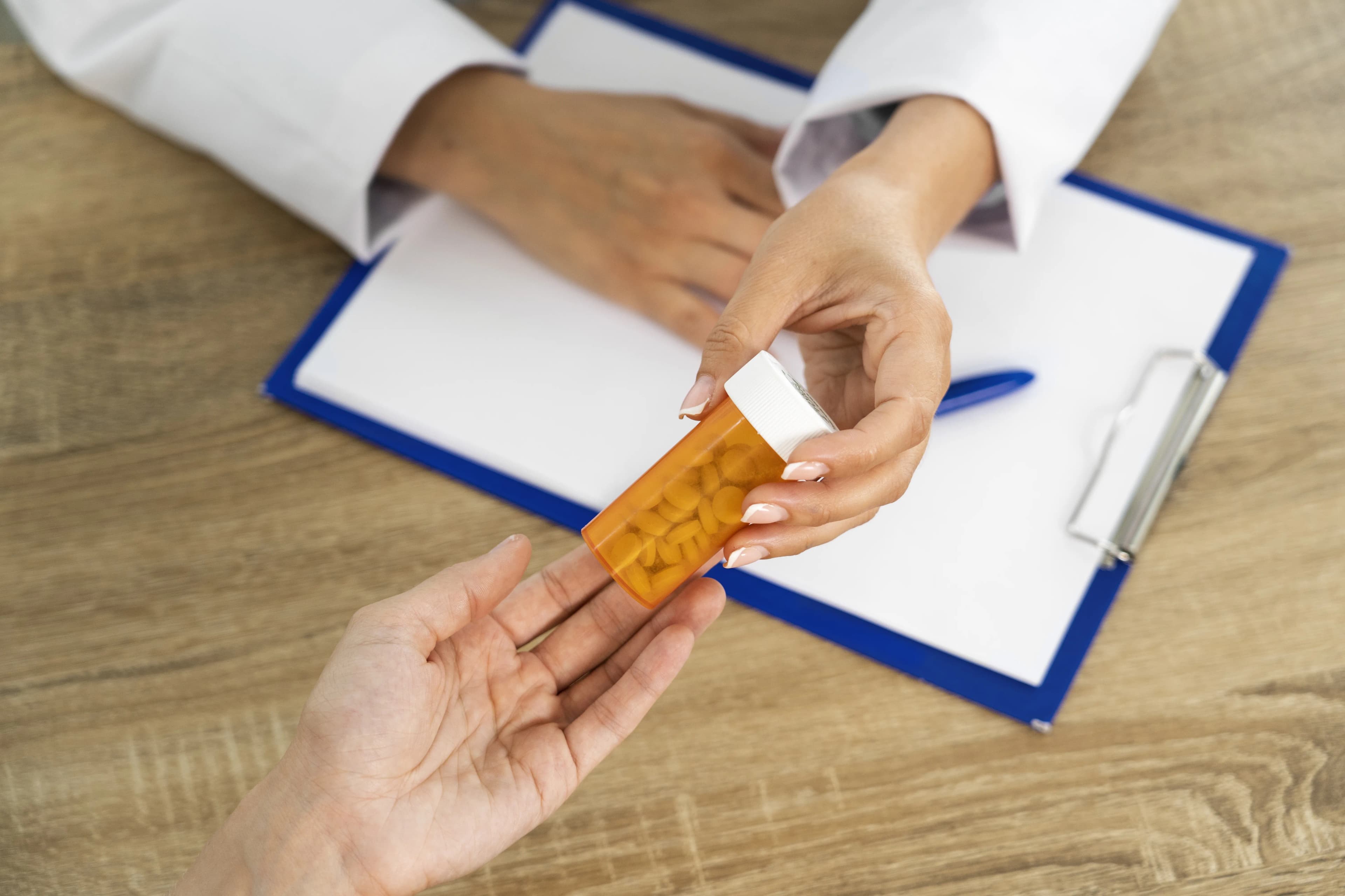 A pharmacist handing a prescription to a patient at the counter